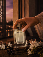 Woman hand holding a Artinz Sanam perfume bottle with a scenic background